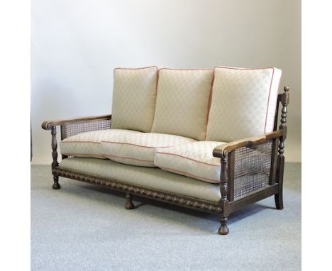 A 1920's oak bergere sofa, with recently upholstered cushions, on turned feet, 183cm