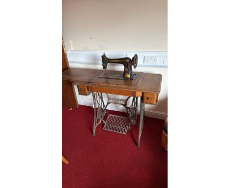 Antique Singer cast iron treadle sewing machine base with ornate gold detailing on black body, featuring Egyptian motifs.