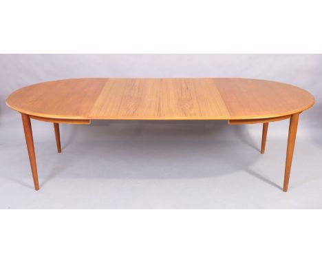 A teak dining table, mid 20th century, with two extra leaves, raised on cylindrical tapering legs, 74cm high, 250cm wide, 105