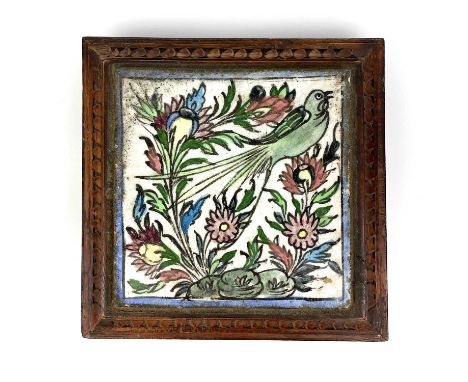 A Persian pottery tile, 19th century. Mounted in an oak stand, on turned feet, size of tile 19 x 18.5cm.