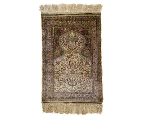 An exceptionally fine Hereke silk rug. The ivory mihrab with signed cartouche and scrolling flowering vines and palmettes, th