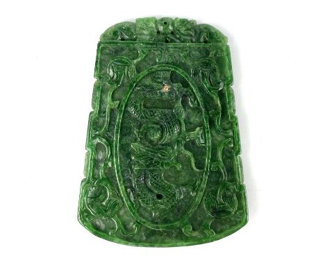 A Chinese spinach green jade type stone pendant. The front carved with a dragon and trailing foliage, 9.9 x 7.3cm.