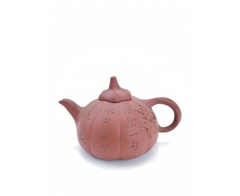 A Chinese Yixing pottery teapot, 19th century. The fluted body with rows of calligraphy, height 10.5cm, length 17.5cm, diamet