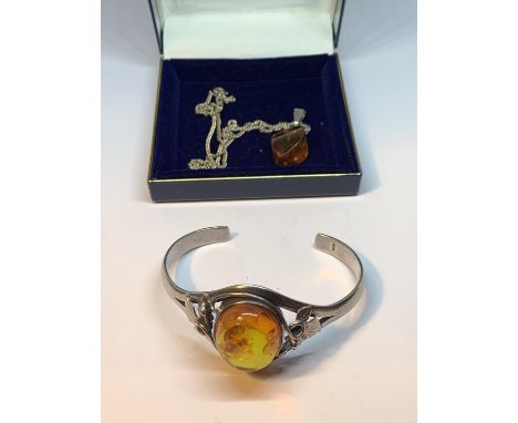 A DECORATIVE SILVER BANGLE WITH A LARGE CENTRAL AMBER STONE AND AN AMBER DROP ON A SILVER CHAIN IN A PRESENTATION BOX 