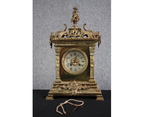 A 19th century ornate Classical design brass mantle clock with putti finial. Silvered dial with Roman numerals in sculpted gi