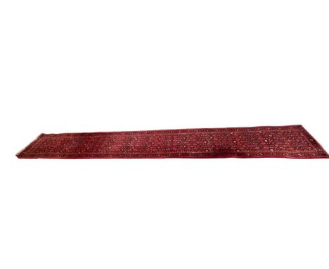 EASTERN RED GROUND WOOLEN RUNNER with repeating central pattern, and triple bordered edge, 500 x 73cmsProvenance: private col