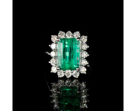 A platinum mounted emerald and diamond cluster ring, the Boyaca Columbian emerald weighing 5.75cts and measuring 12x8mm, surr