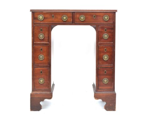 A unusually proportioned George III kneehole writing desk, with eight drawers, the pedestals with doors to reverse, on bracke