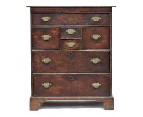 A late 17th/early 18th century joined oak chest of drawers, with an arrangement of seven drawers, panelled sides, on later br