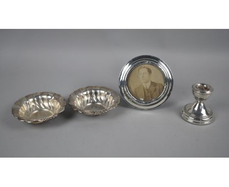 A Small Silver Candlestick, Two Pressed White Metal Dishes Stamped Silver and a Circular Silver Mounted Easel Backed Photo Fr