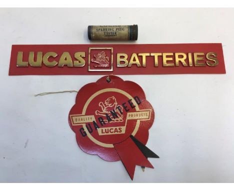 A Lucas Batteries plastic shelf strip and a Lucas Quality Products Guaranteed card rosette, also a Lucas sparking plug tester