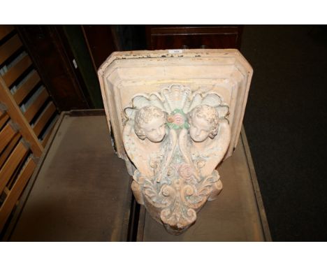 A painted plaster architectural wall bracket with angel detail, 47cm wide