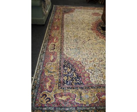 A large Tabriz style Persian carpet with ivory ground with fighting animals and central lozenge within meandering border, 360