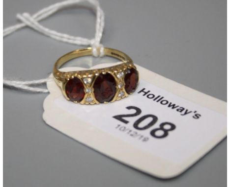 A three stone garnet half-hoop ring, the oval cut garnets with diamond detail and carved 18ct gold mount, 5.6g, Ring size O