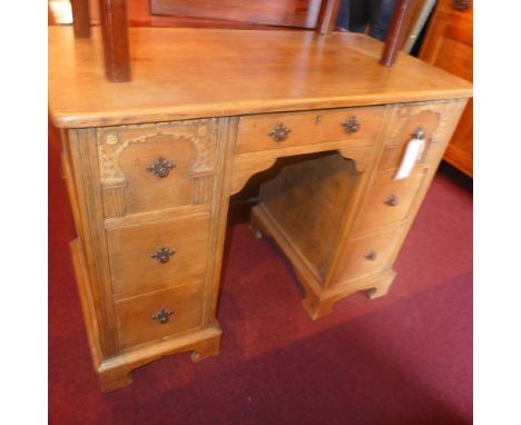 An early 20th century carved oak kneehole desk fitted seven drawers and raised on bracket feet