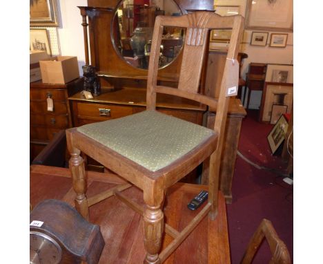 A set of four Art Deco carved oak dining chairs with drop in seats and raised on stretchered supports 