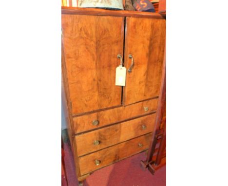 An Art Deco quarter veneered side cabinet, having two cupboard doors over three long graduated drawers raised on squat cabrio