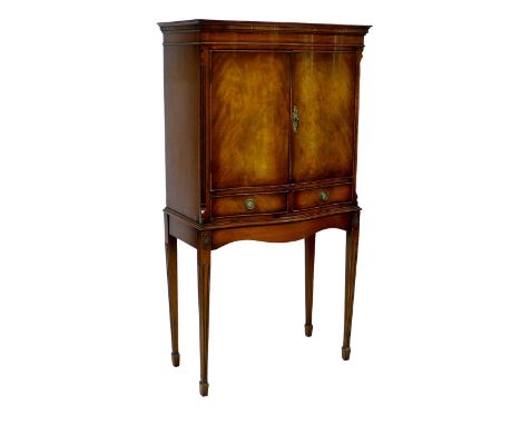 A late 20th century cocktail cabinet, in George III style, with serpentine front, walnut veneers, twin doors opening to revea