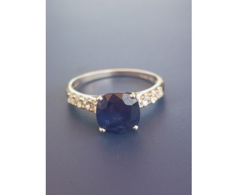 A modern sapphire solitaire ring, in four claw setting with small diamonds to shoulders, 14ct white gold.  Finger size M.