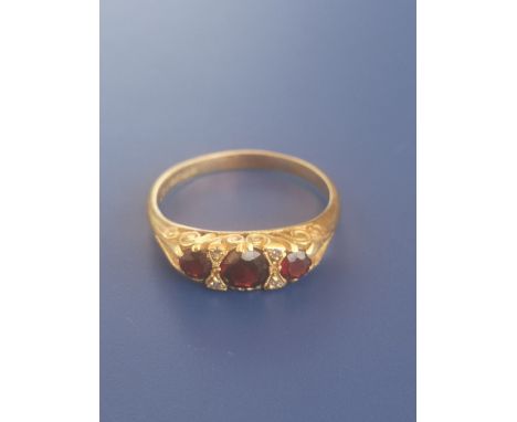 A three stone garnet set 18ct gold ring with diamond spacers - Birmingham marks.  Finger size Q.