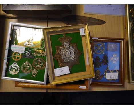 A group of British military cap, shoulder cross belt badges and buckle, mounted in five frames, including 9th Queens Royal La