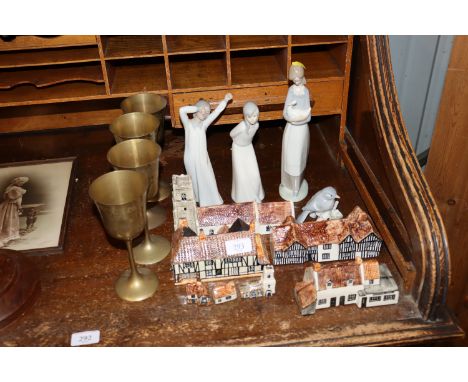 Three Nao figurines; a similar bird ornament; Tey Pottery cottages; and four brass goblets 