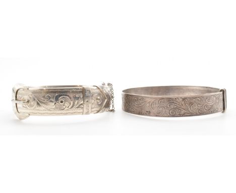 Two silver hallmarked bangle bracelets. The lot to include a hinged bangle with engraved scrolled detailing and belt buckle. 