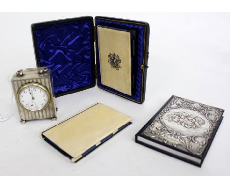 A CHESTER SILVER TIMEPIECE with engine turned decoration and three card cases / notebooks, one with silver cherub embossed fr