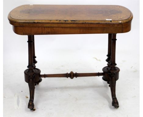 A VICTORIAN WALNUT AND BOXWOOD INLAID FOLD OVER CARD TABLE with turned supports and scrolling legs terminating in ceramic cas