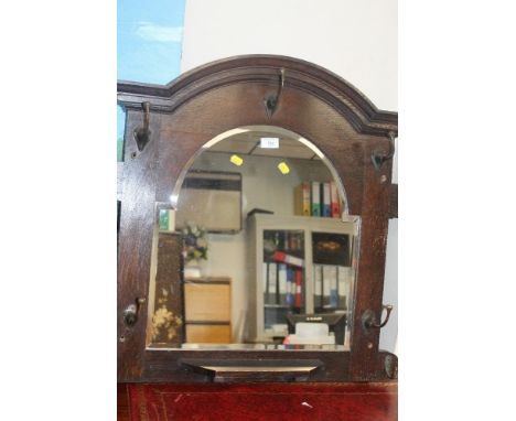 AN OAK HANGING MIRROR WITH COAT HOOKS