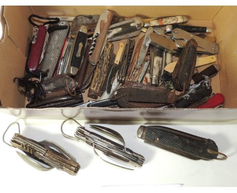 A quantity of folding knives, some military with blades and marlin spike; two multi tool with spoon and fork; some souvenir a