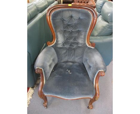 A Victorian walnut armchair having blue button back upholstery, with scrolled arms and castors 