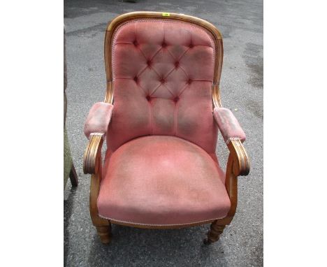 A Victorian walnut button back armchair standing on turned front legs 