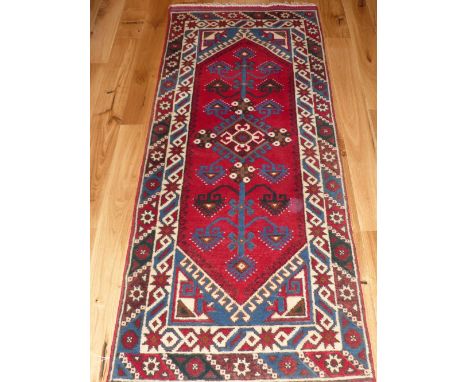 Turkish red ground runner, geometric design, within arched medallion, multicoloured border, 180 x 75cm