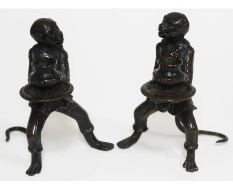 A pair of bronze candlesticks each formed as a fully clothed monkey and holding a platter, height 16.5cm.  