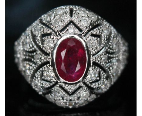 An 18ct white gold ruby and diamond ring, the central oval cut ruby approx. 0.97ct. surrounded by forty two round brilliant c