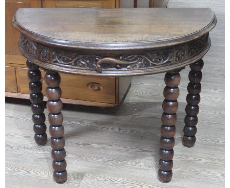 A Victorian demi-lune oak console table, the frieze and drawer carved with leaves, Gothic style quatrefoils and lizard handle