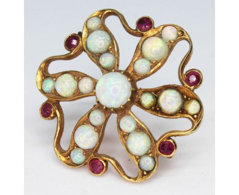 A yellow metal brooch of flower form and set with opal cabochons and ruby coloured stones, diam. 27mm, unmarked, gross wt. 5,