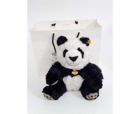 A Steiff Manschli Panda Bear 25cm no. 064258, with button to ear, tags, Steiff box and paper bag. 