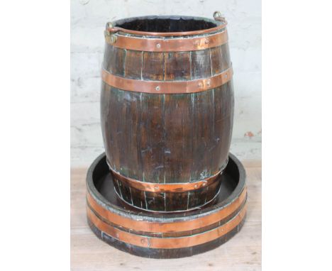 A copper bound planter of barrel form with loop handle and stand, height 53cm.  