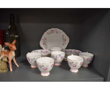 A collection of mid century cups, saucers,cake plate and more, having pink rose pattern and gilt detailing.