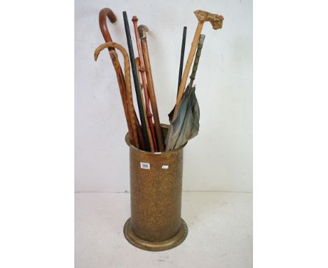 An ornately engraved brass stick stand together with a collection of sticks. 
