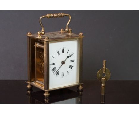 An antique brass case carriage clock with white enamel dial and brass key. 
