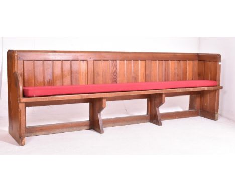 An early 20th century pine ecclesiastic church pew settle bench. The bench having a panelled back with shelf to back. Straigh