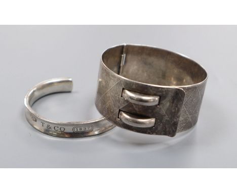 A Tiffany 925 cuff bangle and an engraved white metal hinged belt style bangle.
