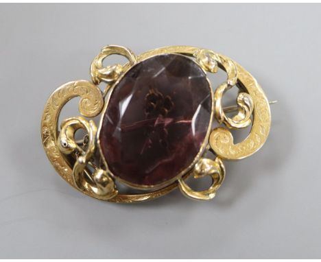 An Edwardian engraved yellow metal mounted amethyst paste set scroll brooch, 43mm.