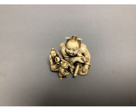   A Japanese ivory netsuke of two miniature men carrying a Samurai's tobacco pouch, Meiji period, signed