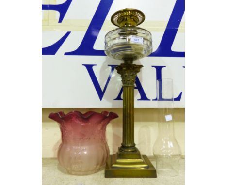 A 19th century Corinthian column oil lamp, reeded brass with glass reservoir and cranberry shade