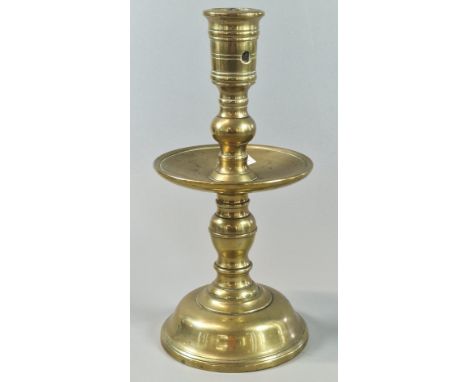17th century brass candlestick, having barrel shaped sconce with wide drip pan on baluster stem with domed base. 19.5cm high 