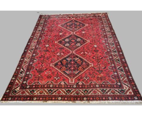 Persian red ground Turkish tribal rug, having three repeating lozenge medallions to the centre, with stylised animal, bird an
